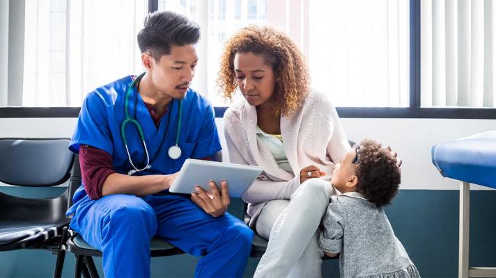 Healthcare worker showing tablet to patient and child Healthcare worker showing tablet to patient and child