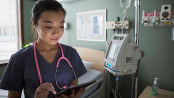 Nurse checks tablet to communicate on shift