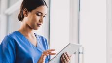 A nurse checking a patient's record on a digital tablet