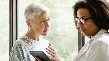 A doctor explaining a senior patient's test results using a digital tablet