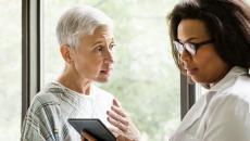 A doctor explaining a senior patient's test results using a digital tablet
