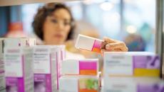 Pharmacist holds and reads a prescription drug box