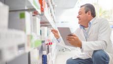 A pharmacist using a digital tablet to do an inventory.