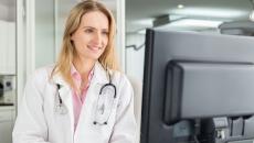 A doctor reviewing a patient's record on a desktop computer