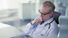 A doctor reviewing a patient's record on a digital tablet.